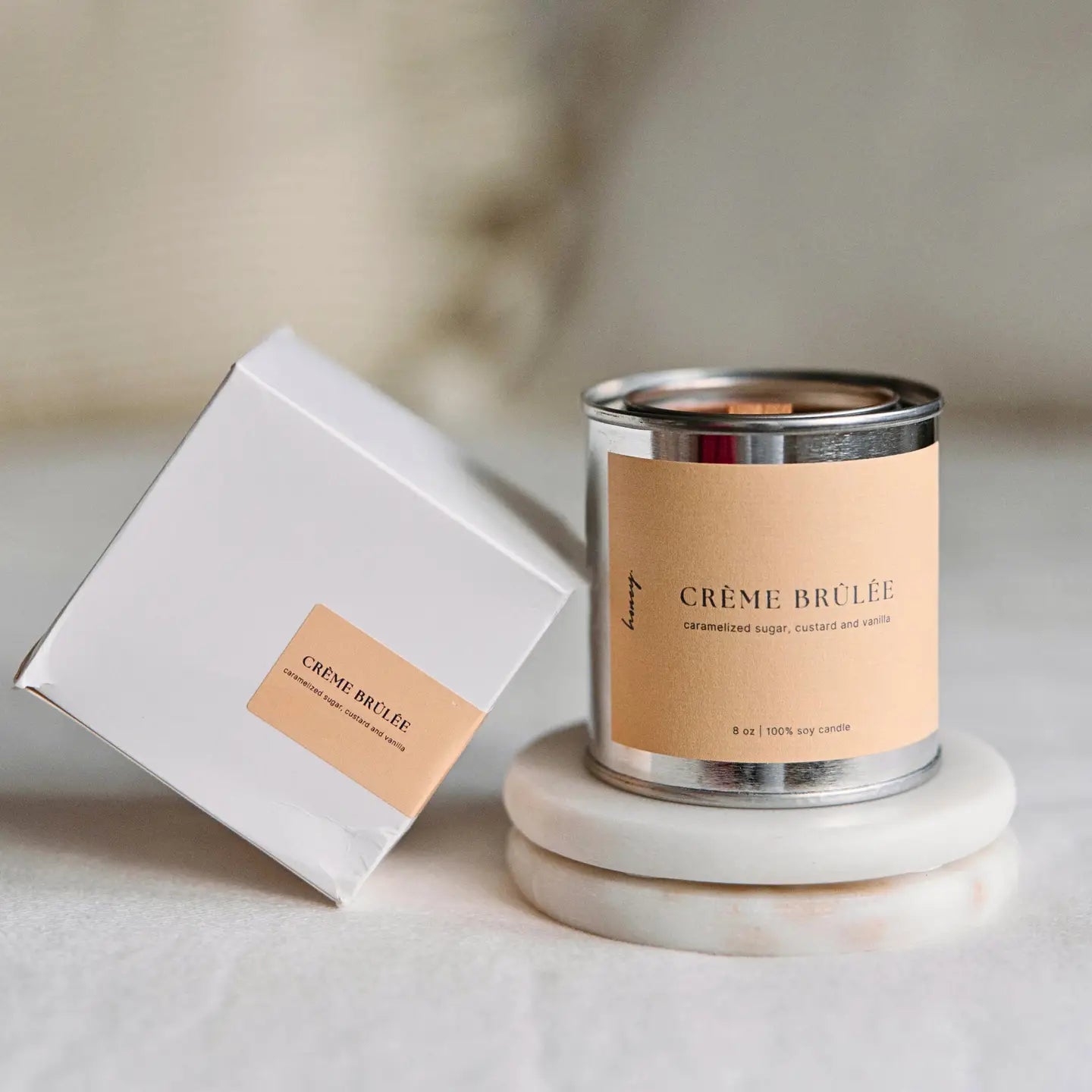 Crème brûlée soy candle with crackling wood wick in reusable tin and minimalist neutral packaging