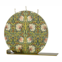 William Morris Pimpernel flat decorative candle featuring intricate botanical floral artwork in green, blush, and gold tones with brass display stand.