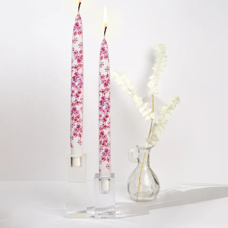 Set of two decorative pink cherry blossom taper candles featuring delicate floral artwork and handcrafted flat candle design.