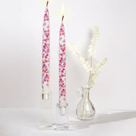 Set of two decorative pink cherry blossom taper candles featuring delicate floral artwork and handcrafted flat candle design.