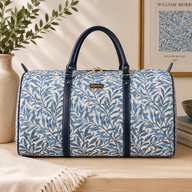 William Morris Willow Bough blue tapestry duffel bag with woven leaf pattern, navy faux leather handles, and spacious weekender holdall design for travel and overnight trips.