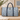 William Morris Willow Bough blue tapestry duffel bag with woven leaf pattern, navy faux leather handles, and spacious weekender holdall design for travel and overnight trips.
