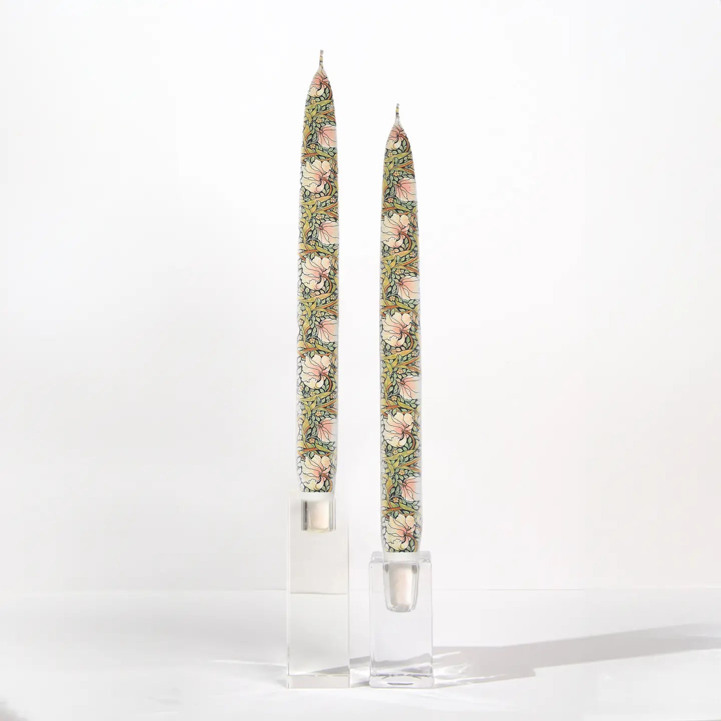 Set of two William Morris Pimpernel decorative taper candles featuring botanical floral artwork in soft sage green, blush, and cream tones.